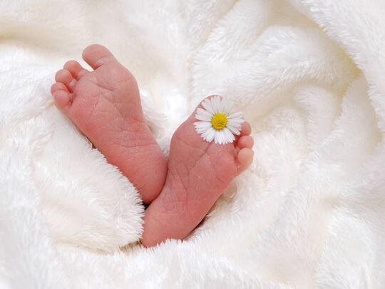 Pieds de bébé avec pâquerette entre les orteils